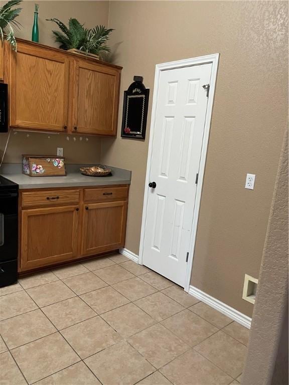 kitchen with black appliances and light tile patterned flooring