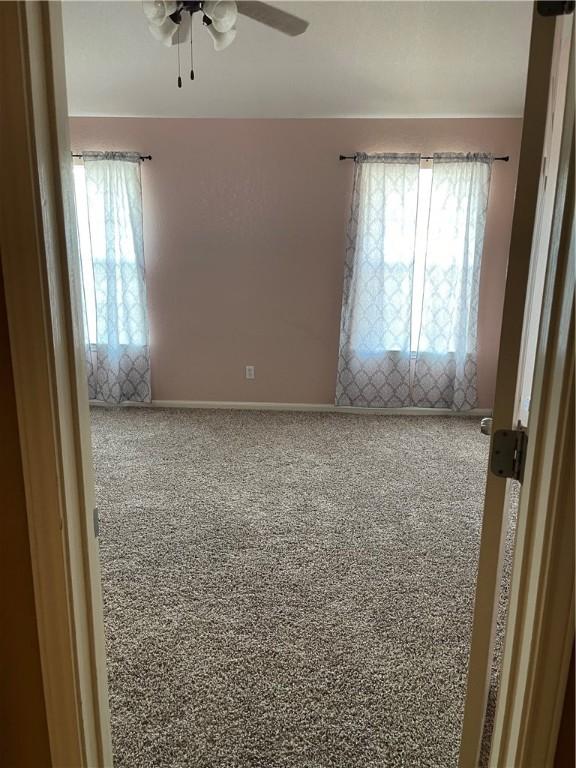 carpeted empty room featuring plenty of natural light and ceiling fan