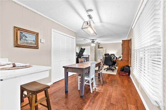 dining space featuring ceiling fan, ornamental molding, a textured ceiling, and hardwood / wood-style flooring