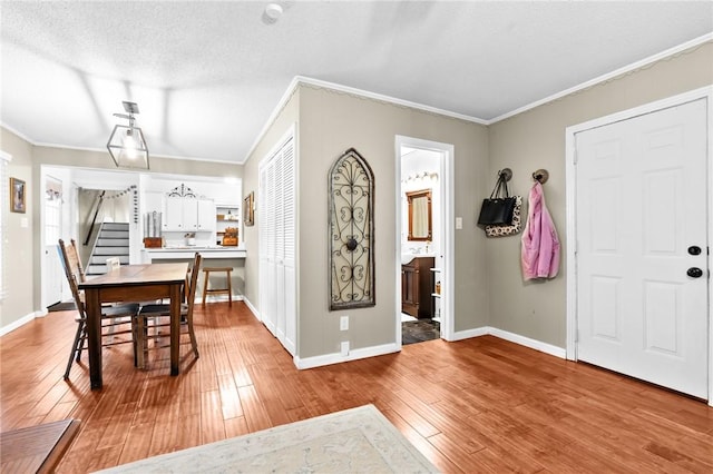 entryway with light hardwood / wood-style flooring, a textured ceiling, and ornamental molding