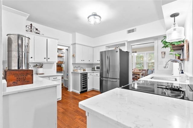 kitchen featuring stainless steel refrigerator, light stone countertops, white cabinetry, hanging light fixtures, and beverage cooler