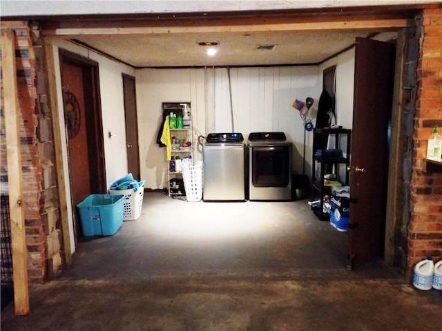 basement featuring washing machine and clothes dryer and brick wall