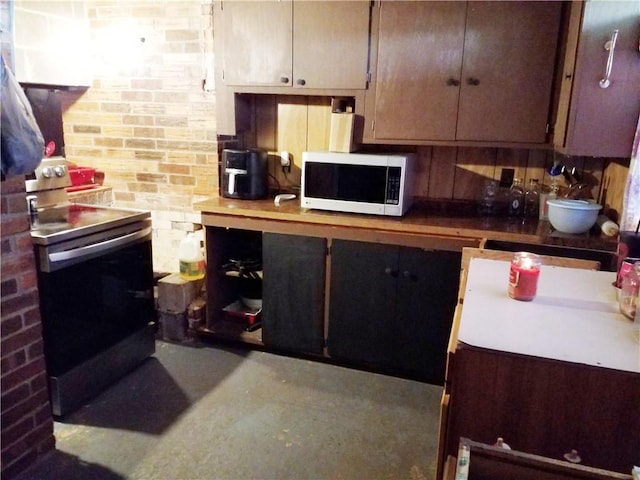 kitchen featuring stainless steel electric range and brick wall