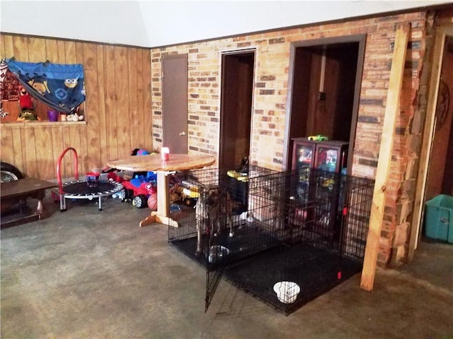 miscellaneous room with brick wall, carpet floors, lofted ceiling, and wood walls