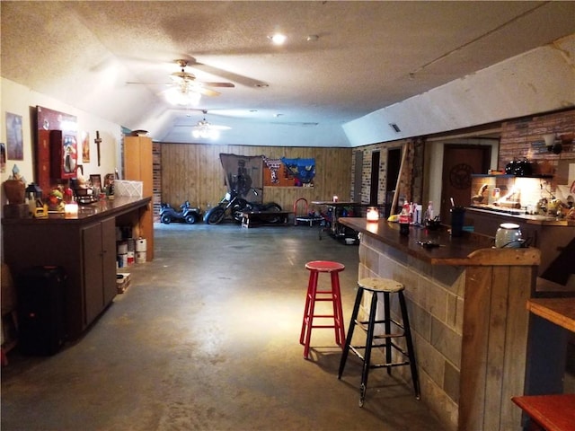 bar featuring wooden walls, ceiling fan, and lofted ceiling