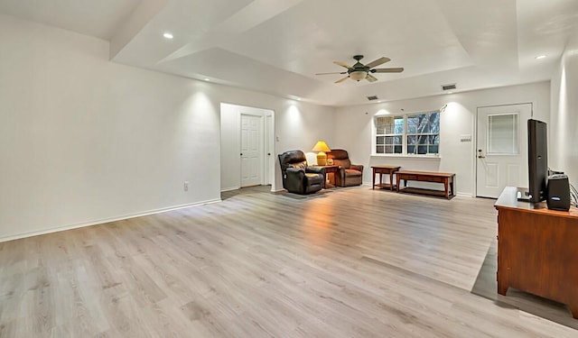 interior space featuring ceiling fan, a raised ceiling, and light hardwood / wood-style flooring