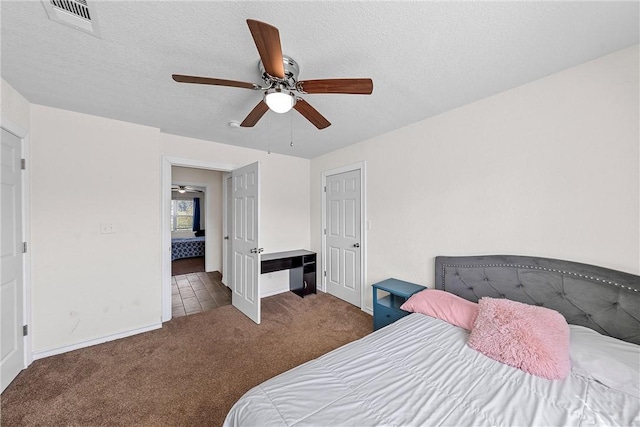 carpeted bedroom featuring ceiling fan and a textured ceiling