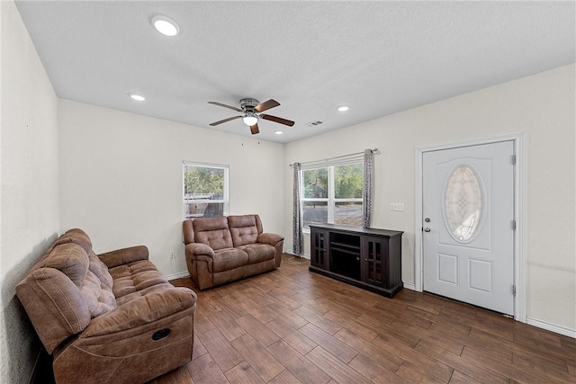 living room featuring ceiling fan, dark hardwood / wood-style flooring, and a textured ceiling