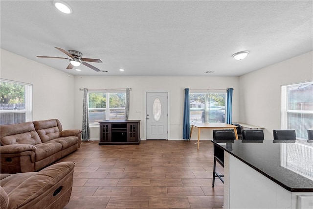 living room with plenty of natural light, dark hardwood / wood-style floors, a textured ceiling, and ceiling fan