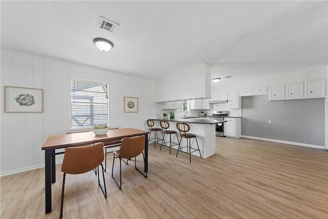 dining space with wood walls and light wood-type flooring