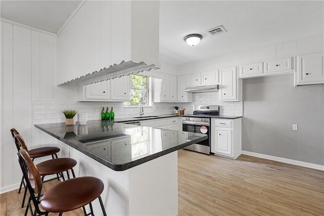 kitchen with stainless steel electric range, a kitchen breakfast bar, kitchen peninsula, light hardwood / wood-style floors, and white cabinetry