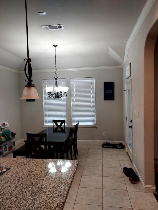 dining area with light tile patterned floors, a notable chandelier, and ornamental molding