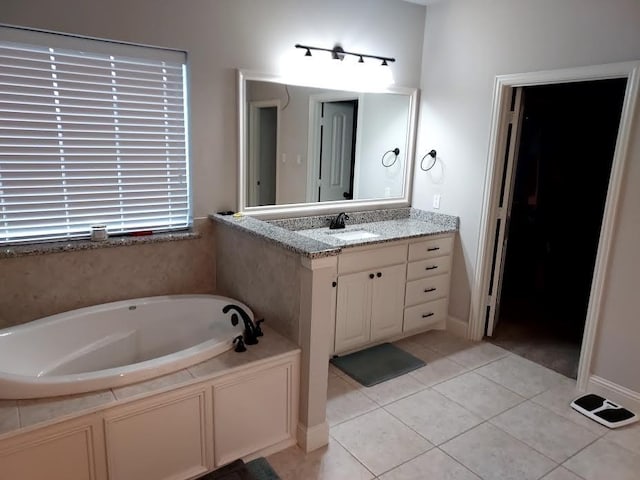 bathroom with tile patterned floors, a tub to relax in, and vanity