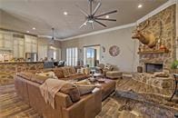 living room featuring a stone fireplace, ornamental molding, and hardwood / wood-style flooring