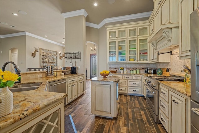 kitchen featuring stainless steel appliances, arched walkways, and cream cabinetry