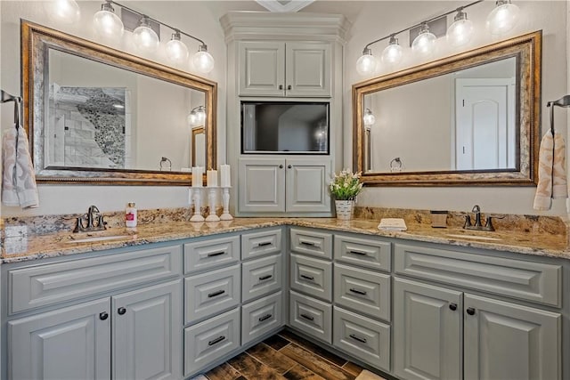 full bath featuring a sink, wood tiled floor, double vanity, and a tile shower