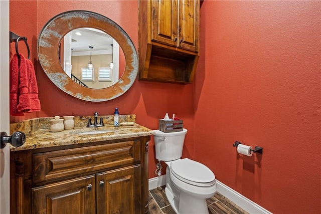 half bath with vanity, toilet, and baseboards