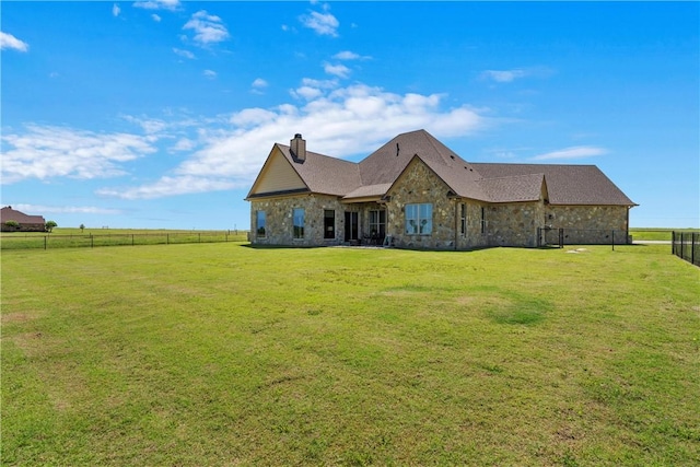 back of property featuring fence, a lawn, stone siding, and a chimney