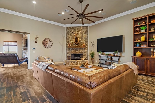 living room featuring a ceiling fan, visible vents, wood tiled floor, a stone fireplace, and crown molding