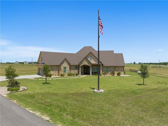 view of front of house featuring a front yard, an attached garage, stone siding, and driveway