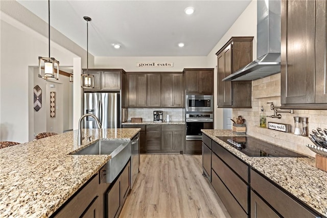 kitchen featuring sink, appliances with stainless steel finishes, light stone counters, decorative backsplash, and wall chimney exhaust hood