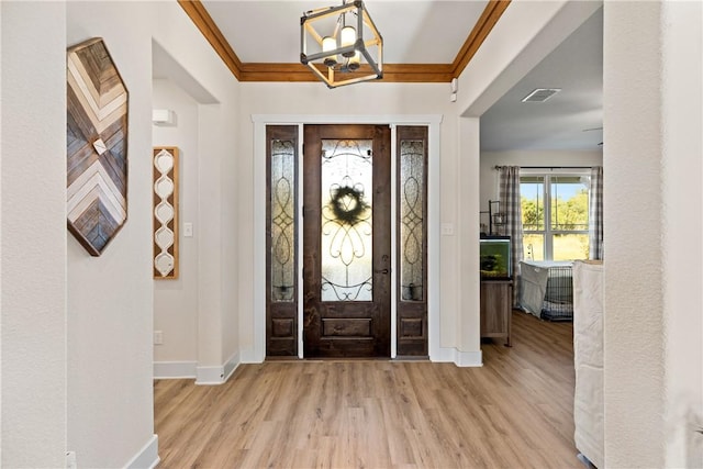 foyer with crown molding, an inviting chandelier, and light hardwood / wood-style flooring