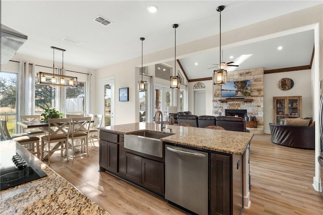 kitchen with sink, a center island with sink, stainless steel dishwasher, and light stone countertops