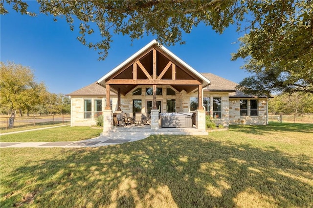 rear view of house with a patio area, a hot tub, and a lawn