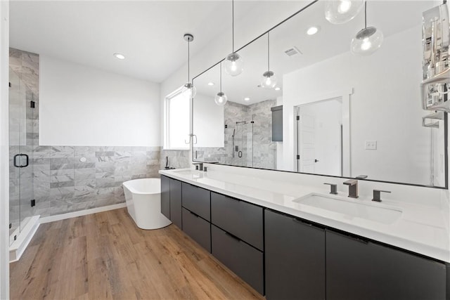 bathroom featuring wood-type flooring, vanity, shower with separate bathtub, and tile walls