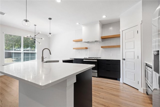 kitchen featuring decorative light fixtures, stainless steel electric range, and an island with sink