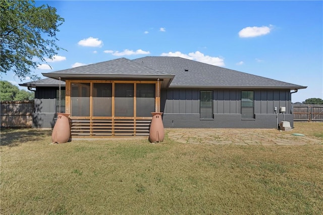 rear view of house featuring a sunroom and a lawn