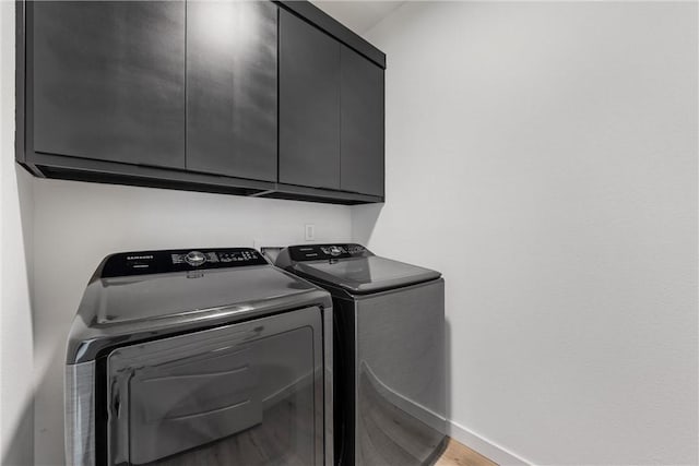 laundry room featuring cabinets, light hardwood / wood-style floors, and washer and dryer