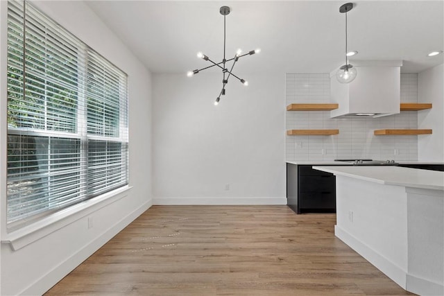 kitchen with decorative light fixtures, light wood-type flooring, and a wealth of natural light