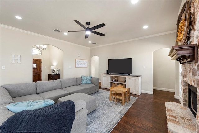 living area featuring visible vents, dark wood-type flooring, a ceiling fan, arched walkways, and baseboards