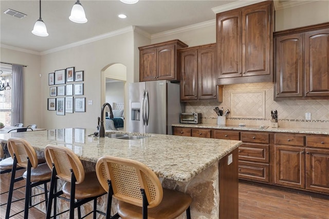 kitchen with visible vents, stainless steel fridge with ice dispenser, dark wood-style floors, arched walkways, and a sink