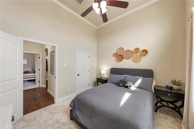 bedroom featuring carpet, baseboards, visible vents, a towering ceiling, and crown molding