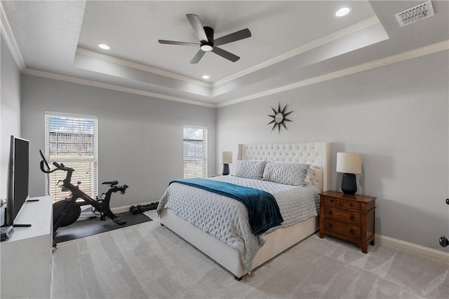 bedroom featuring a tray ceiling, baseboards, light colored carpet, and crown molding