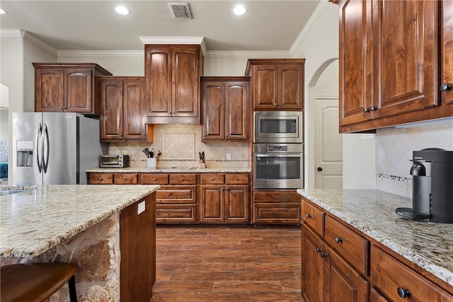 kitchen with light stone counters, visible vents, dark wood-style flooring, stainless steel appliances, and tasteful backsplash