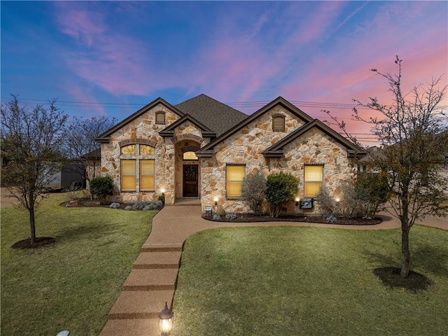 french country home with a front lawn and stone siding