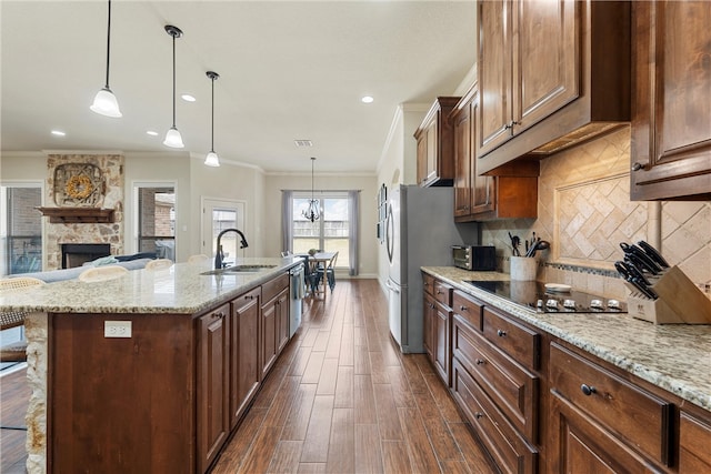 kitchen featuring an island with sink, a sink, tasteful backsplash, dark wood-style floors, and black electric cooktop