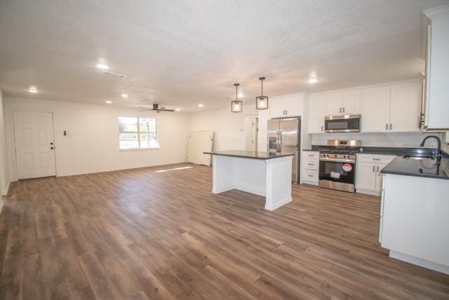 kitchen featuring sink, appliances with stainless steel finishes, decorative light fixtures, a kitchen island, and white cabinetry