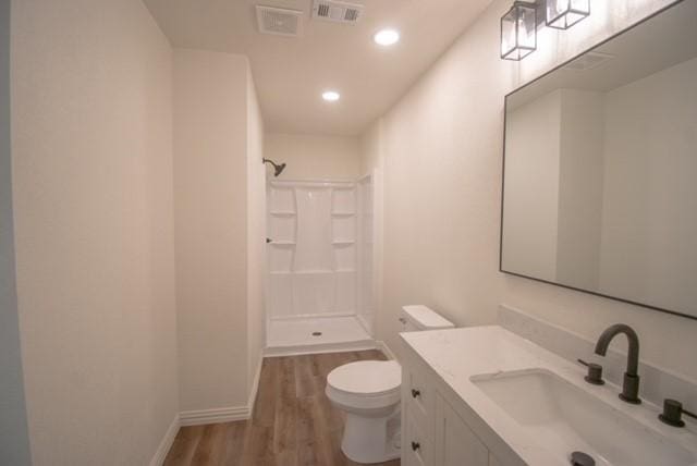 bathroom featuring a shower, wood-type flooring, vanity, and toilet