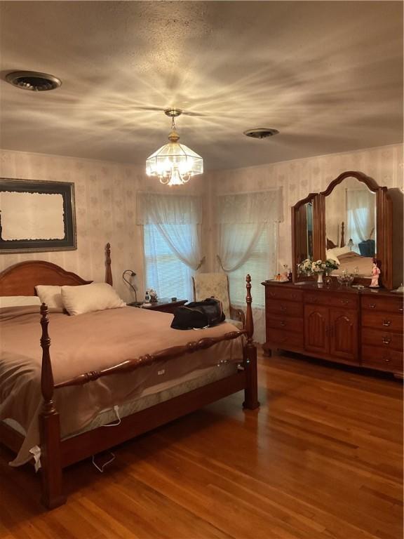 bedroom with hardwood / wood-style floors and an inviting chandelier