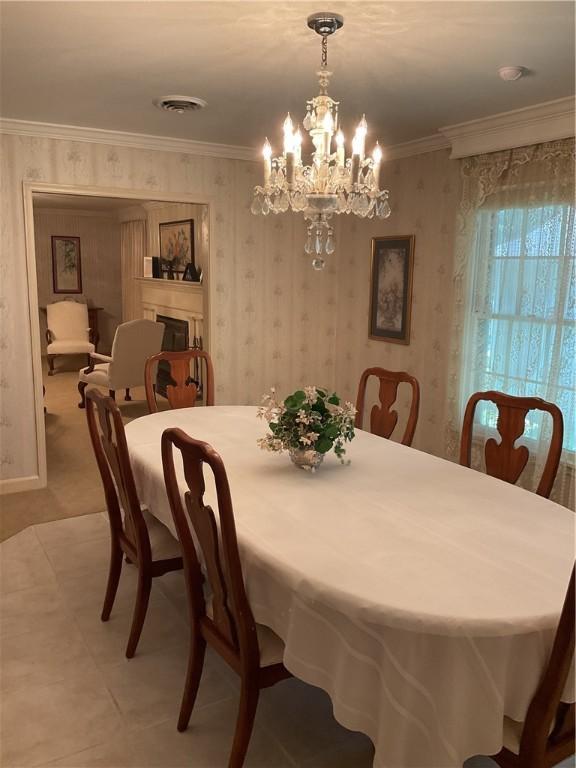 tiled dining area featuring crown molding and a chandelier