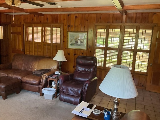 tiled living room with wood walls, ceiling fan, and a healthy amount of sunlight