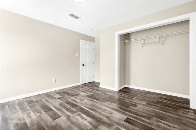 unfurnished bedroom with dark hardwood / wood-style flooring and a closet