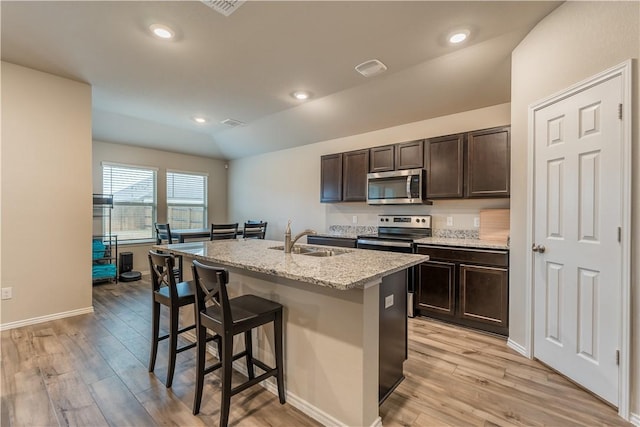 kitchen featuring appliances with stainless steel finishes, lofted ceiling, sink, a kitchen island with sink, and dark brown cabinetry