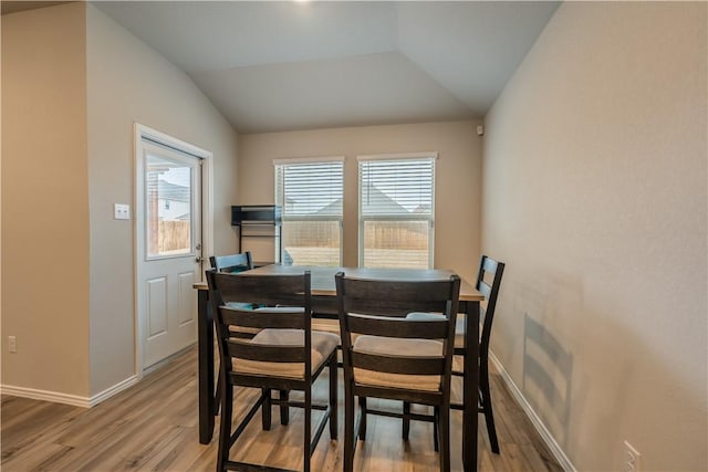 dining area with hardwood / wood-style flooring and vaulted ceiling