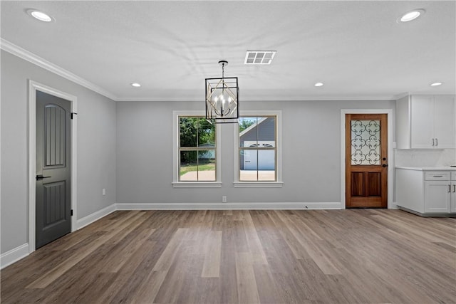 unfurnished dining area featuring an inviting chandelier, light hardwood / wood-style flooring, and crown molding