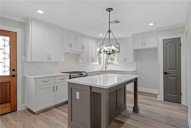 kitchen with ornamental molding, sink, a center island, light hardwood / wood-style floors, and white cabinetry